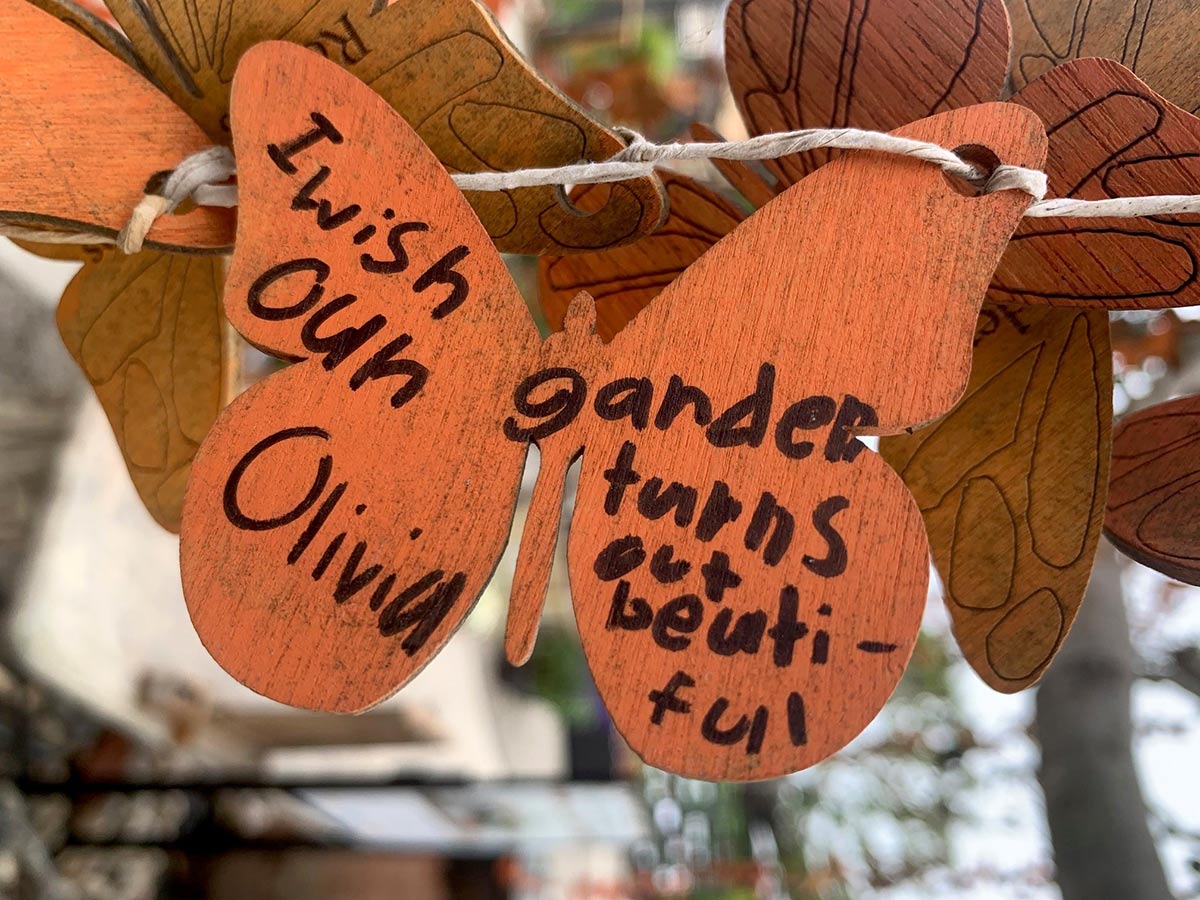 Wooden butterfly with written wish: I wish our garden turns out beautiful