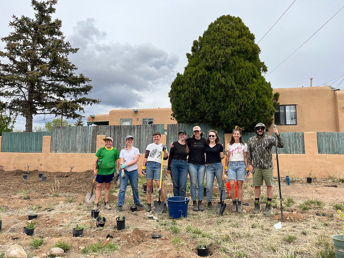 Volunteers with shovels and other gardening gear standing in front of pollinator habitat in progress