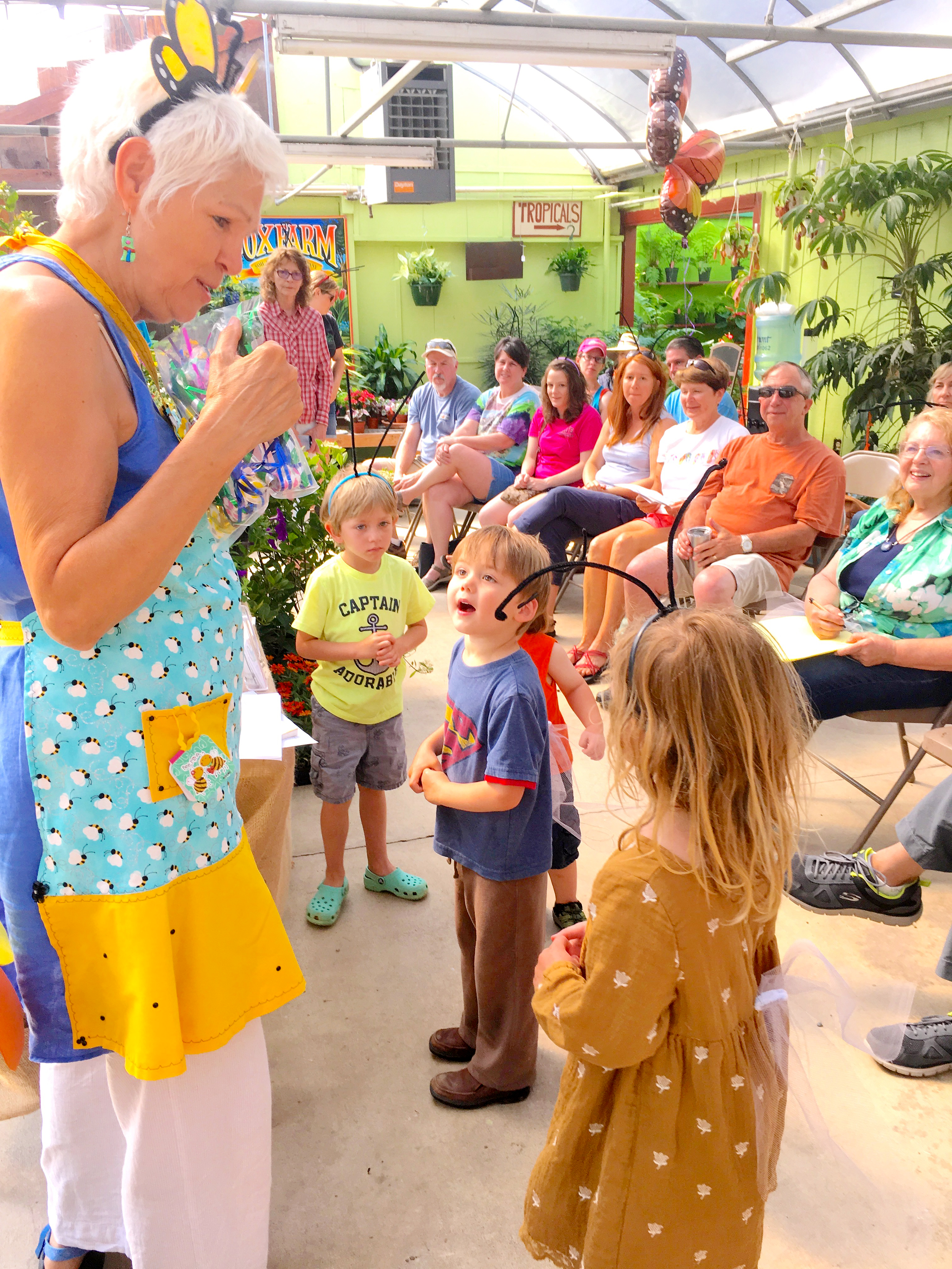 A woman in a colorful outfit dances with kids at an outdoor event.