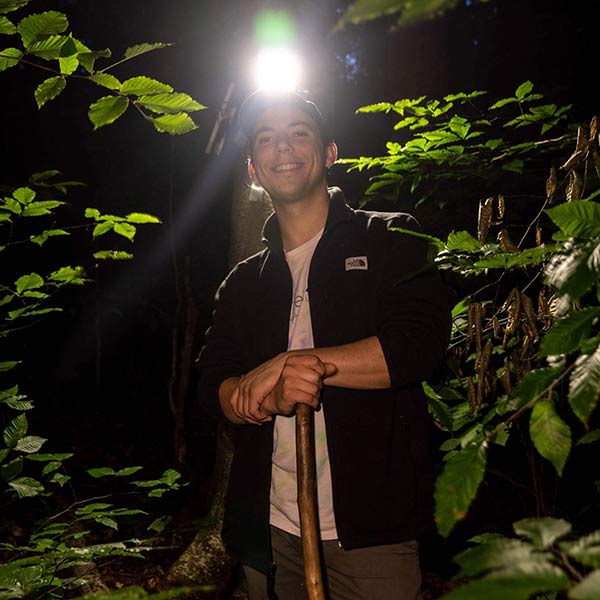 John Dreitsch standing amid trees in darkness with a headlamp on