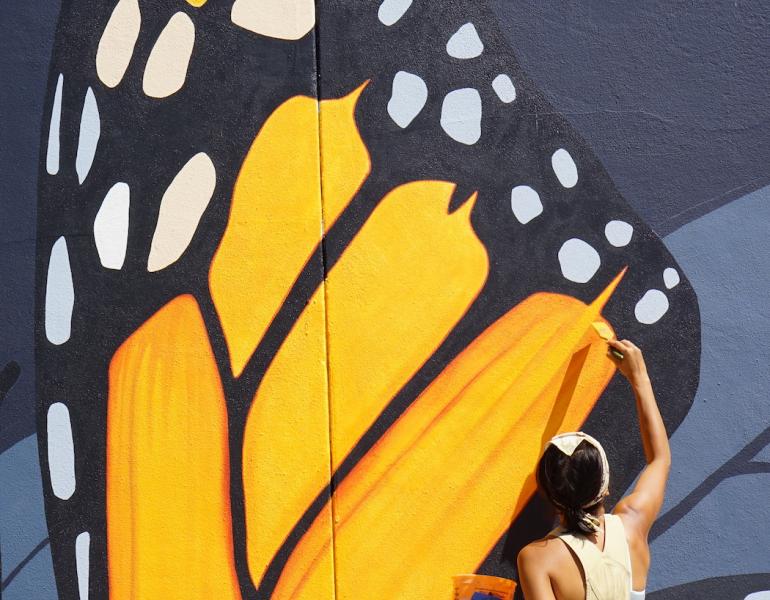 Artist Jane Kim of Ink Dwell studio paints the wing of a giant monarch butterfly, part of the Midnight Dream mural in downtown Orlando, Florida.