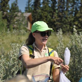 The author stands in a field holding a net while talking during a demonstration.