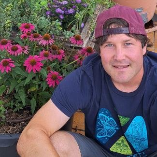Jochen wearing Xerces Society shirt sitting in front of blooming flowers in several containers
