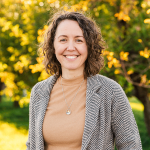 Emily May standing outdoors and smiling